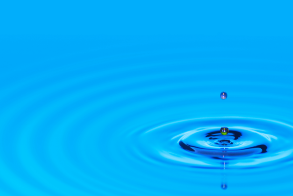 a droplet of water creating a ripple on a blue body of water